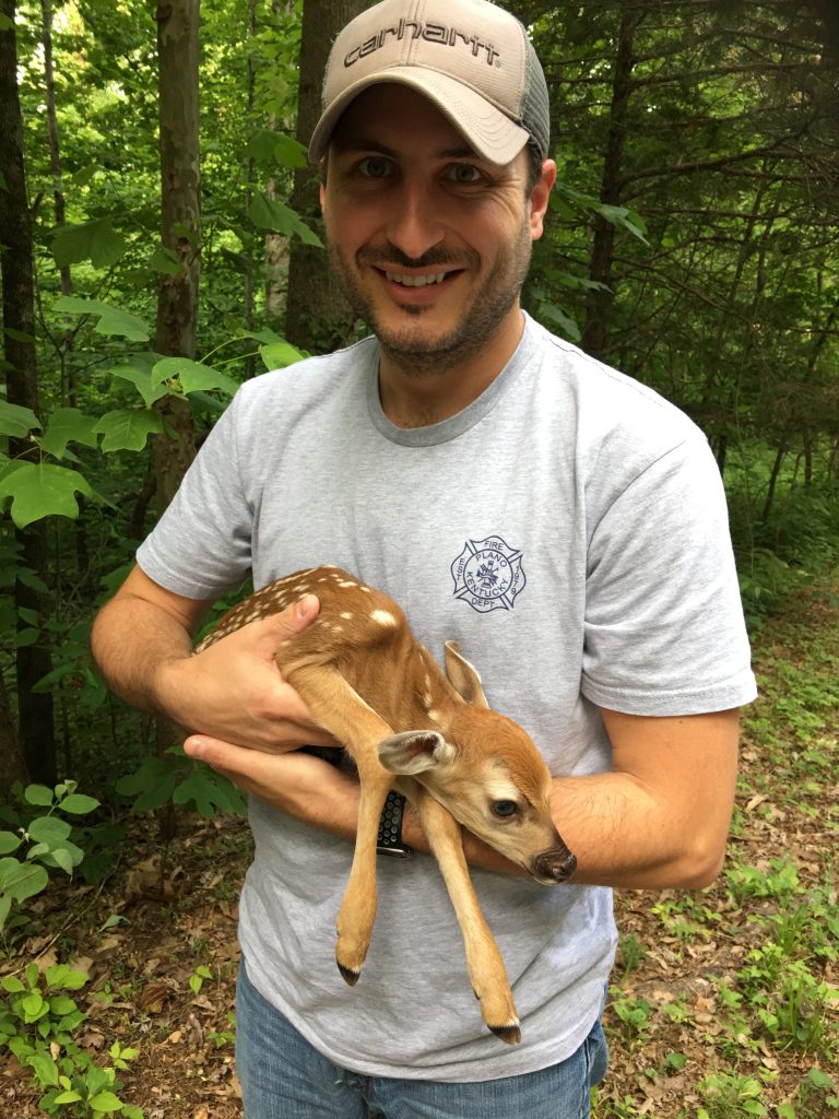 photo of man holding baby fawn